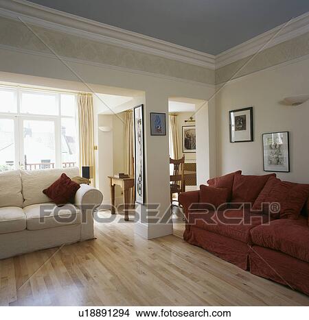 Picture - Red and cream sofas in cream living room with laminated wood flooring. Fotosearch