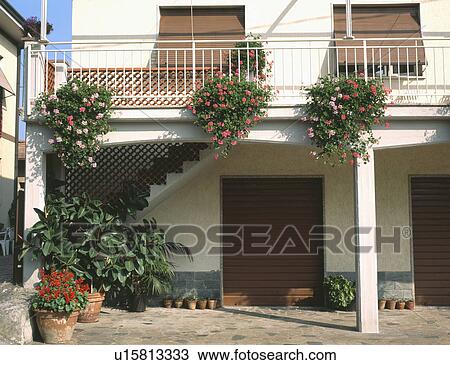 Stock Image - Red and pink geraniums on balcony above courtyard of Turkish house. Fotosearch