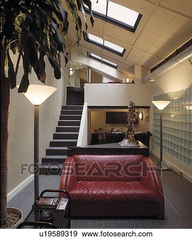 Stock Photo - Red leather sofa and uplighters in open plan hall with glass bricks and staircase in loft conversion. Fotosearch