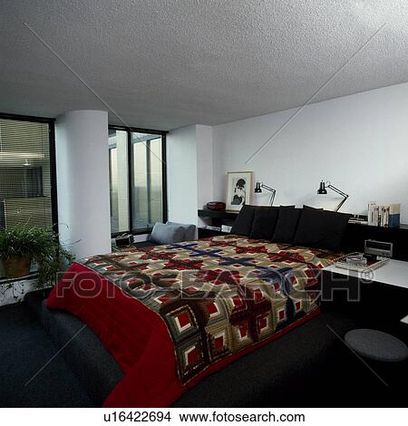 Red patchwork quilt on bed in modern white bedroom View Large Photo Image Picture - Red patchwork quilt on bed in modern white bedroom. Fotosearch