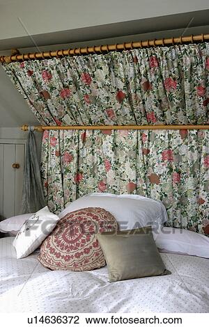 Ruched floral curtain on pole behind bed with cushions and white linen View Large Photo Image Stock Image - Ruched floral curtain on pole behind bed with cushions and white linen. Fotosearch