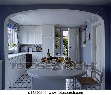 Rush-seated stools at island breakfast bar in pastel blue kitchen with white fitted cupboards View Large Photo Image Stock Image - Rush-seated stools at island breakfast bar in pastel blue kitchen with white fitted cupboards. Fotosearch