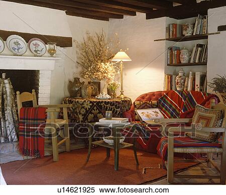 Rush-seated wooden chairs and red sofa in cottage living room with lighted lamp on table in corner of the room View Large Photo Image Stock Photography - Rush-seated wooden chairs and red sofa in cottage living room with lighted lamp on table in corner of the room. Fotosearch