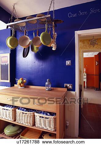 Saucepans on storage rack above wooden cupboard with storage baskets in bright blue kitchen View Large Photo Image Stock Photo - Saucepans on storage rack above wooden cupboard with storage baskets in bright blue kitchen. Fotosearch