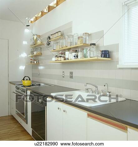 Shelves above double white sink in modern white galley kitchen View Large Photo Image Stock Image - Shelves above double white sink in modern white galley kitchen. Fotosearch