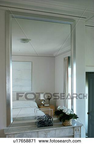 Silver mirror with reflection of monochromatic uncluttered modern bedroom View Large Photo Image Stock Image - Silver mirror with reflection of monochromatic uncluttered modern bedroom. Fotosearch