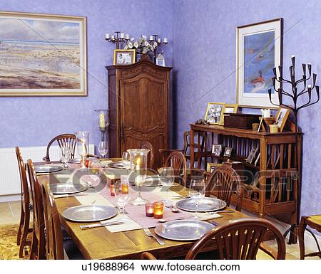 Picture - Silver plates and lighted candles on gold tablecloth in blue dining room with corner cupboard. Fotosearch