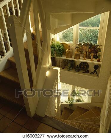 Stock Photo - Sisal carpet on staircase below window with wicker bottles on shelves . Fotosearch