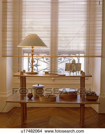 Picture - Slatted blind above plywood table with lamp. Fotosearch