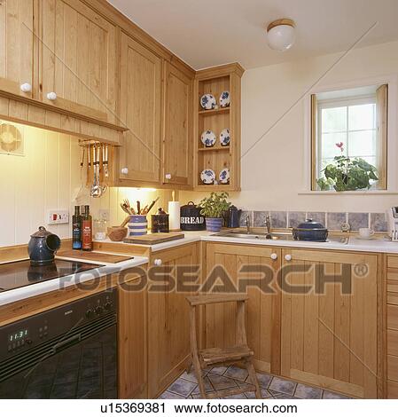 Stock Image - Small country kitchen with pine cupboards and units. Fotosearch