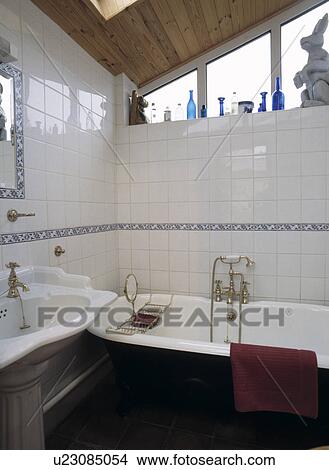 Picture - Small modern white tiled bathroom with roll-top bath . Fotosearch