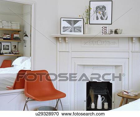 Small white spare bedroom with red stacking chair and traditional fireplace. View Large Photo Image Stock Image - Small white spare bedroom with red stacking chair and traditional fireplace.. Fotosearch