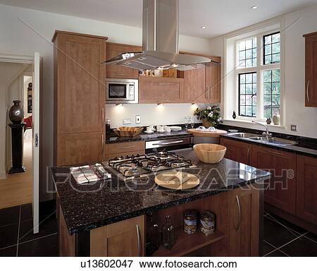 Stainless steel extractor above gas hob in island unit with black granite worktop in modern kitchen View Large Photo Image Stock Photo - Stainless steel extractor above gas hob in island unit with black granite worktop in modern kitchen. Fotosearch