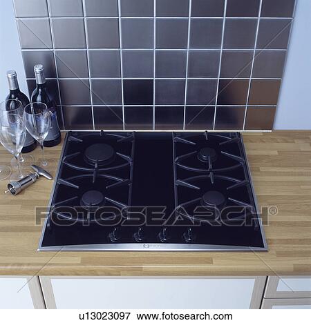 Stock Photo - Stainless steel wall tiles above black gas hob set into wooden worktop &#13; &#10; &#13; &#10; &#13; &#10; &#13; &#10; &#13; &#10; &#13; &#10;. Fotosearch