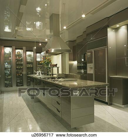 Stock Photo - Steel extractor above granite worktop on island unit in modern grey kitchen with pale grey floor tiles . Fotosearch