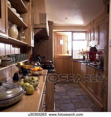 Stone Floor Tiles In Narrow Country Kitchen With Wooden Units And