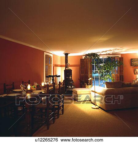 Stock Photograph - Stove in traditional living and dining room lit at night. Fotosearch