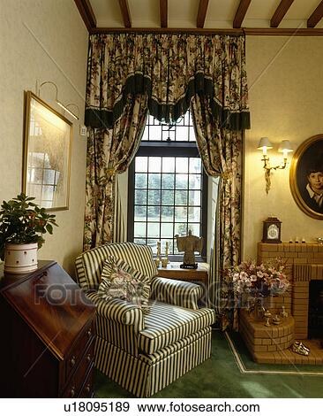 Striped armchair in living room with swagged floral curtains View Large Photo Image Stock Photo - Striped armchair in living room with swagged floral curtains. Fotosearch