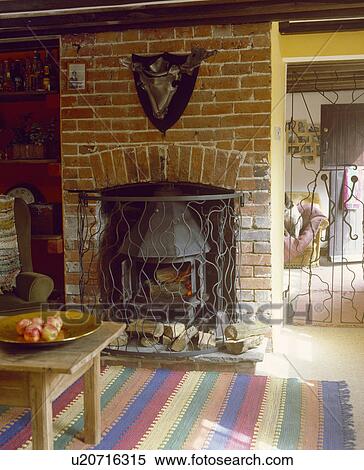 Striped Rug In Front On Brick Fireplace With Cast Iron Stove In