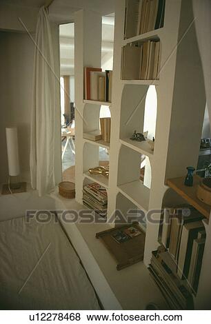 Stock Photo - Sunken bed below open plaster bookshelves. Fotosearch