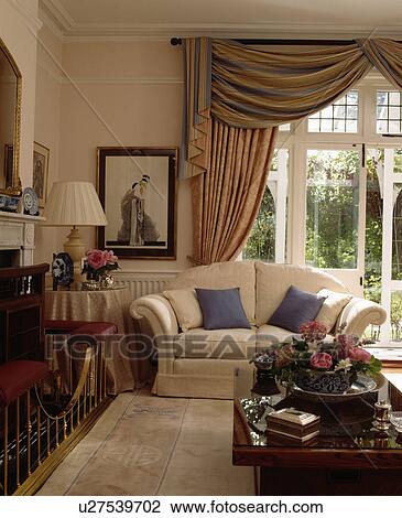 Stock Image - Swagged patterned curtains in traditional living room. Fotosearch