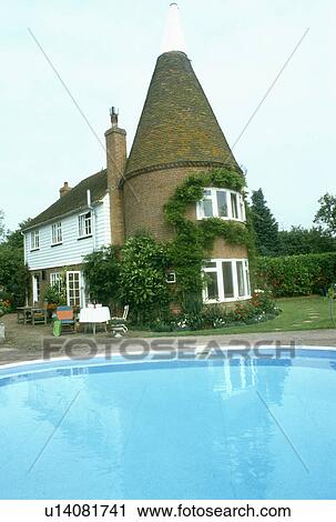 Stock Image - Swimming pool in front of traditional converted oasthouse. Fotosearch