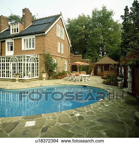Swimming pool with paved edge in front of traditional country house View Large Photo Image Picture - Swimming pool with paved edge in front of traditional country house. Fotosearch
