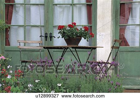 Table and chairs in front of French windows in country garden in summer View Large Photo Image Stock Photo - Table and chairs in front of French windows in country garden in summer. Fotosearch