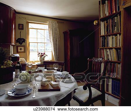 Table set for lunch with cheeses and white cloth in small traditional diningroom with bookshelves View Large Photo Image Picture - Table set for lunch with cheeses and white cloth in small traditional diningroom with bookshelves. Fotosearch
