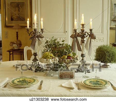Table with wineglasses and plates with candles in tall candelabra and fruit decoration on white tablecloth View Large Photo Image Stock Photo - Table with wineglasses and plates with candles in tall candelabra and fruit decoration on white tablecloth. Fotosearch
