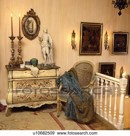 Tall candlesticks and statue on antique painted chest of drawers on landing with throw on gilt antique chair View Large Photo Image Stock Photo - Tall candlesticks and statue on antique painted chest of drawers on landing with throw on gilt antique chair. Fotosearch