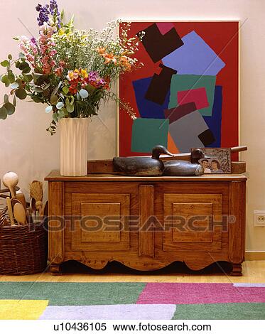 Tall flower arrangement and large abstract painting above pine chest View Large Photo Image Stock Photography - Tall flower arrangement and large abstract painting above pine chest. Fotosearch