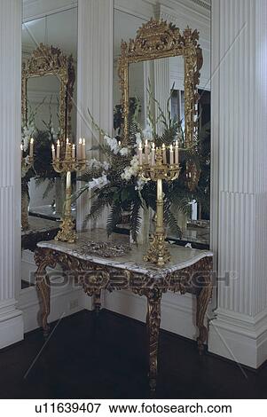 Tall gilt candlesticks on baroque marble and gilt table in front of mirrored wall in traditional hall View Large Photo Image Stock Photo - Tall gilt candlesticks on baroque marble and gilt table in front of mirrored wall in traditional hall. Fotosearch