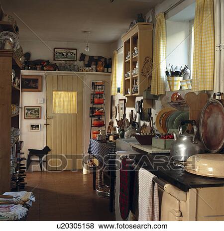 Stock Photo - Tea towels on cream Aga in cottage kitchen with yellow door with glazed panel. Fotosearch