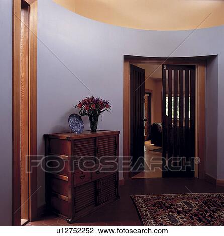 Teak chest of drawers in modern grey circular hall with open door to living room View Large Photo Image Stock Image - Teak chest of drawers in modern grey circular hall with open door to living room. Fotosearch