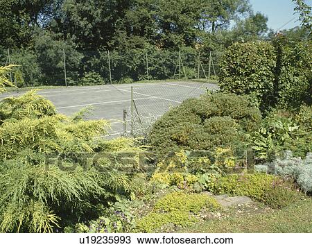 Stock Image - Tennis court in large country garden. Fotosearch