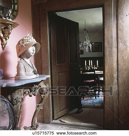Stock Photography - Thirties bust on console table in cottage hall with door open to dining room. Fotosearch