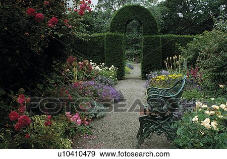Stock Photo - Topiary arch and clipped hedge in large country garden in summer. Fotosearch