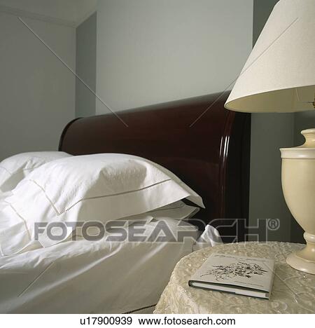 Traditional bedroom with a dark wood headboard, white bed linen and cream bedside lamp View Large Photo Image Stock Photo - Traditional bedroom with a dark wood headboard, white bed linen and cream bedside lamp. Fotosearch
