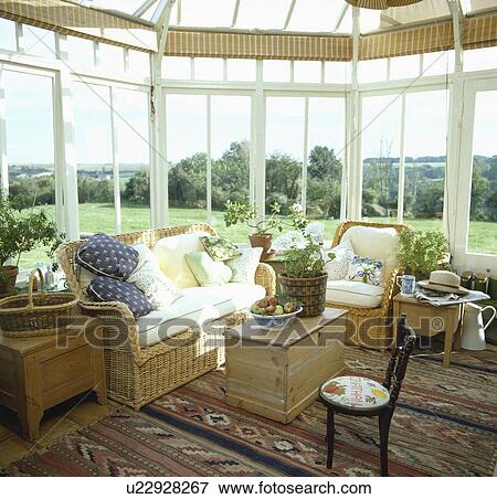Stock Photo - Traditional conservatory living room with comfortable furniture and green plants. Fotosearch