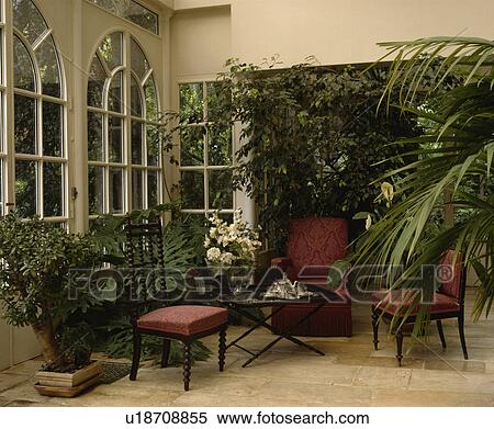 Stock Photography - Traditional conservatory living room with comfortable furniture and green plants. Fotosearch