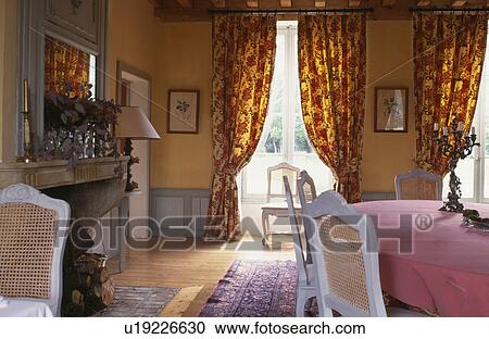 Stock Image - Traditional country diningroom with yellow and red curtains&#13; &#10; &#13; &#10;. Fotosearch