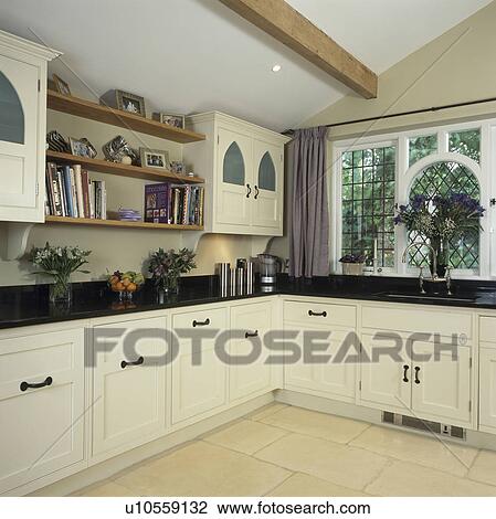 Stock Image - Traditional kitchen extension with white cupboards and black worktops. Fotosearch
