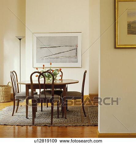 Traditional table and chairs in modern white dining room with large picture View Large Photo Image Stock Photo - Traditional table and chairs in modern white dining room with large picture. Fotosearch