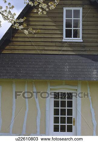 Stock Image - Traditional white and cream timbered country cottage in France. Fotosearch