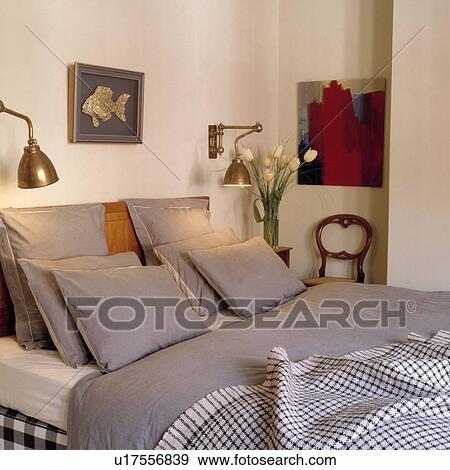 Stock Photo - Traditional white bedroom with brass wall lamps and grey bed linen. Fotosearch