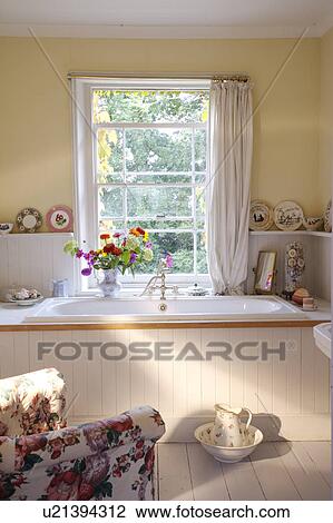 Stock Image - Traditional yellow bathroom with white painted panelling around bath and below dado . Fotosearch