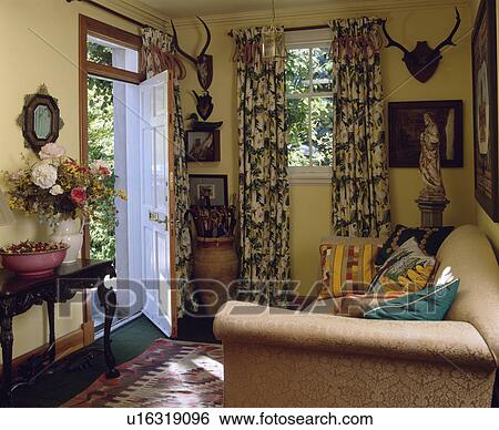 Traditional yellow cottage living room with patterned curtains and cream sofa View Large Photo Image Stock Photograph - Traditional yellow cottage living room with patterned curtains and cream sofa. Fotosearch