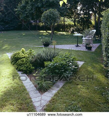 Triangular beds with paved edging in large lawn in country garden in summer View Large Photo Image Stock Photo - Triangular beds with paved edging in large lawn in country garden in summer. Fotosearch