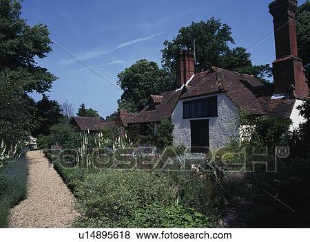 Stock Photo - Tudor country cottage with long borders either side of front path.. Fotosearch